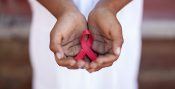 Child's hands holding an HIV awareness ribbon, Cape Town, South Africa